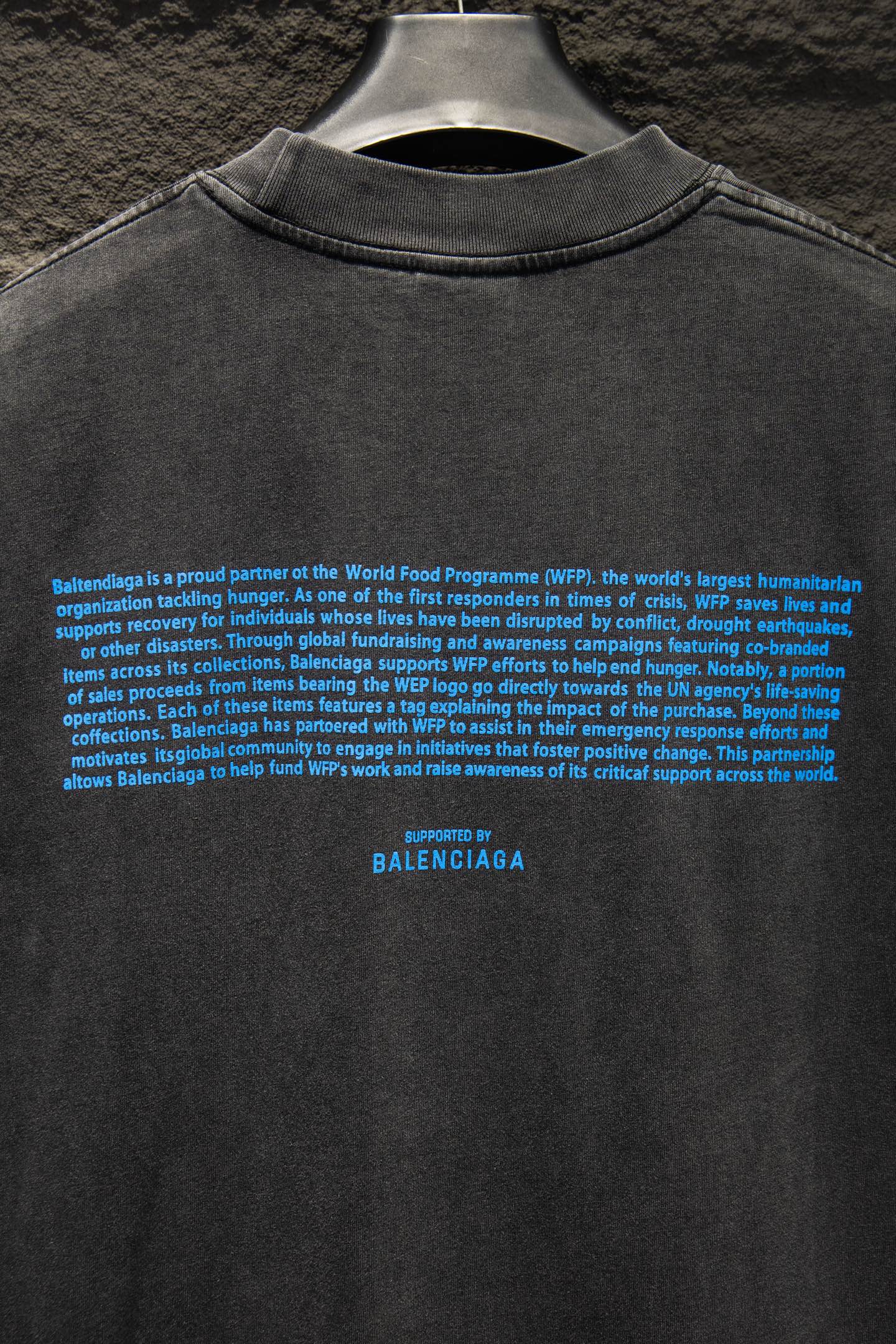 Gray T-shirt back with dense blue text and “BALENCIAGA” near hem