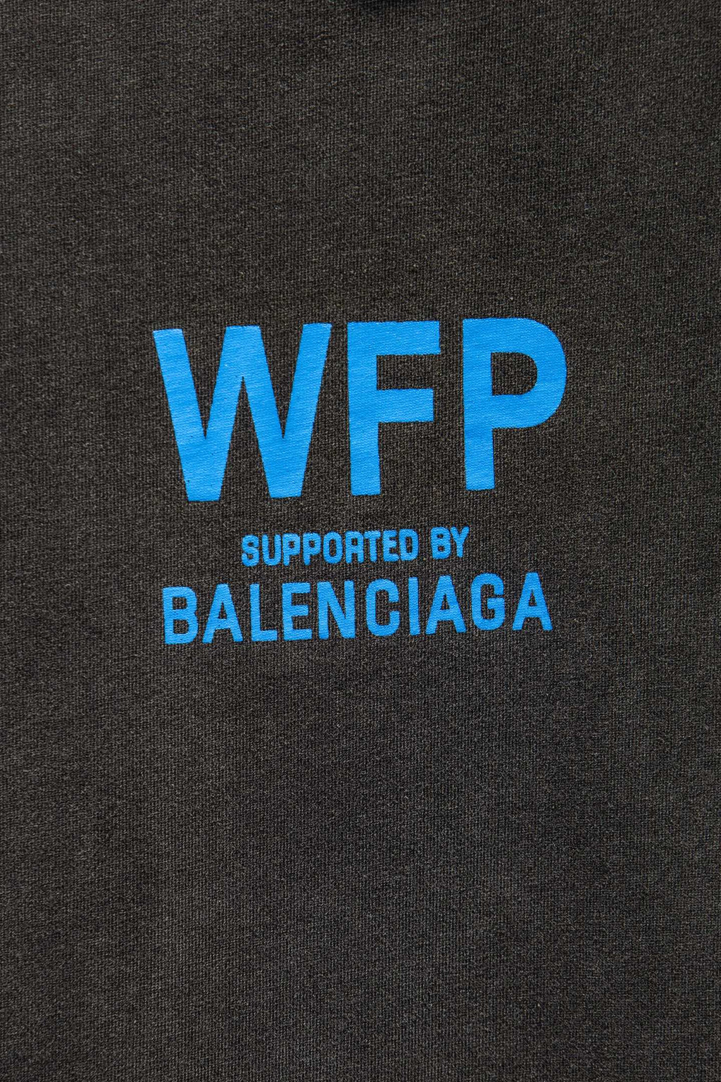 Gray T-shirt chest with large blue “WFP” and “SUPPORTED BY BALENCIAGA”