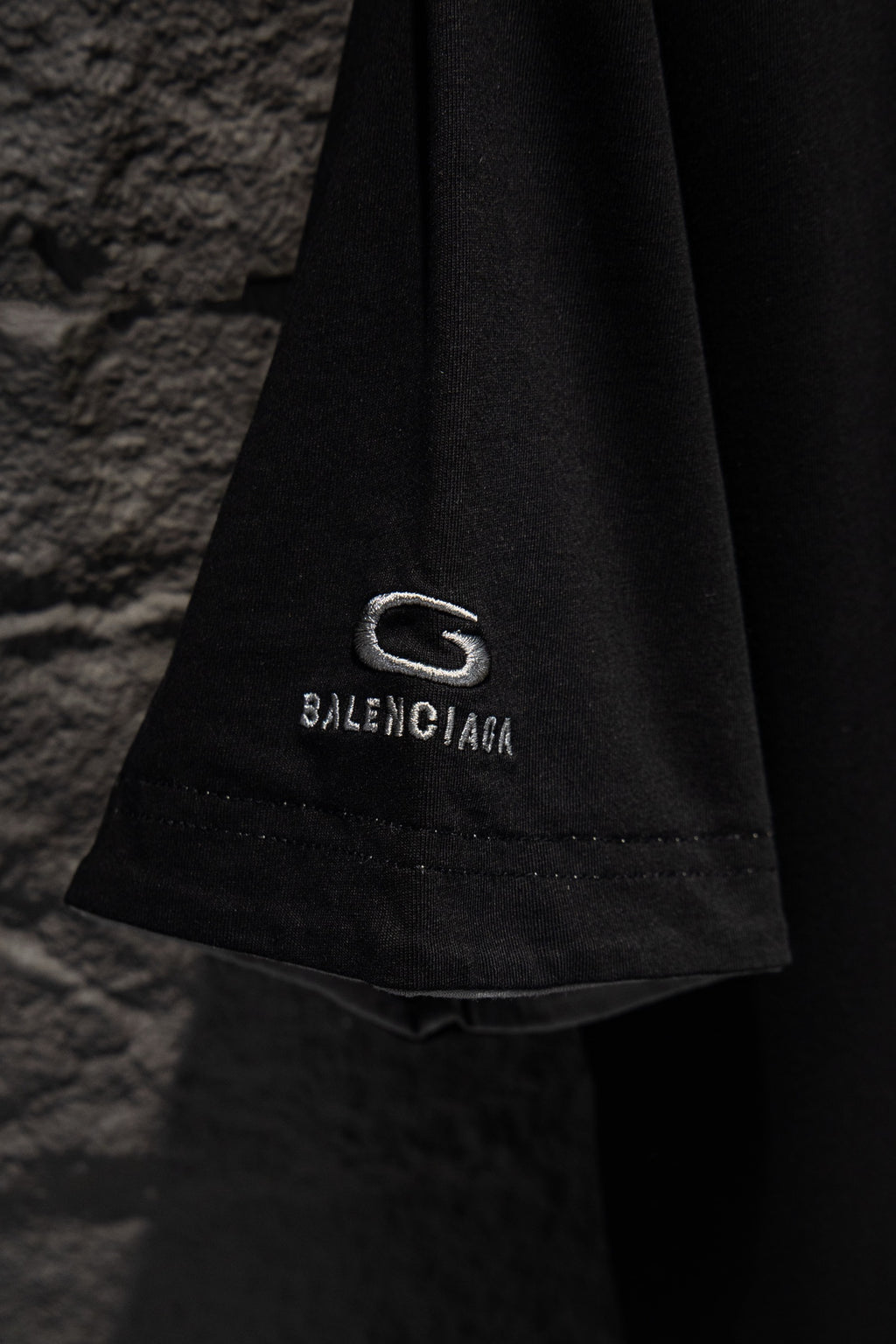 Balenciaga black T-shirt hem detail with G logo patch and BALENCIAGA text