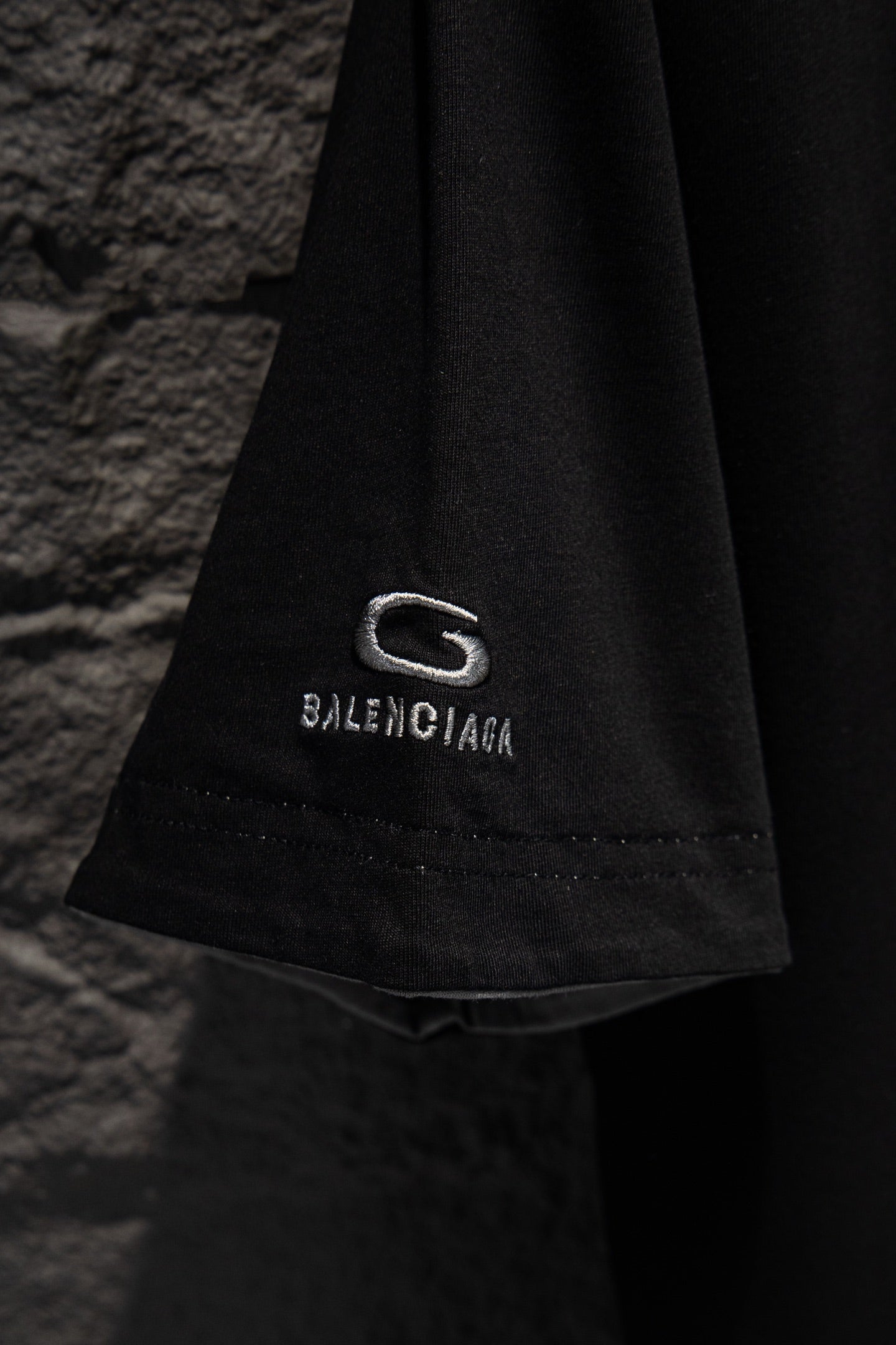 Balenciaga black T-shirt hem detail with G logo patch and BALENCIAGA text