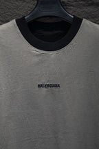 Balenciaga T-shirt neckline close-up, light gray with black collar trim and logo