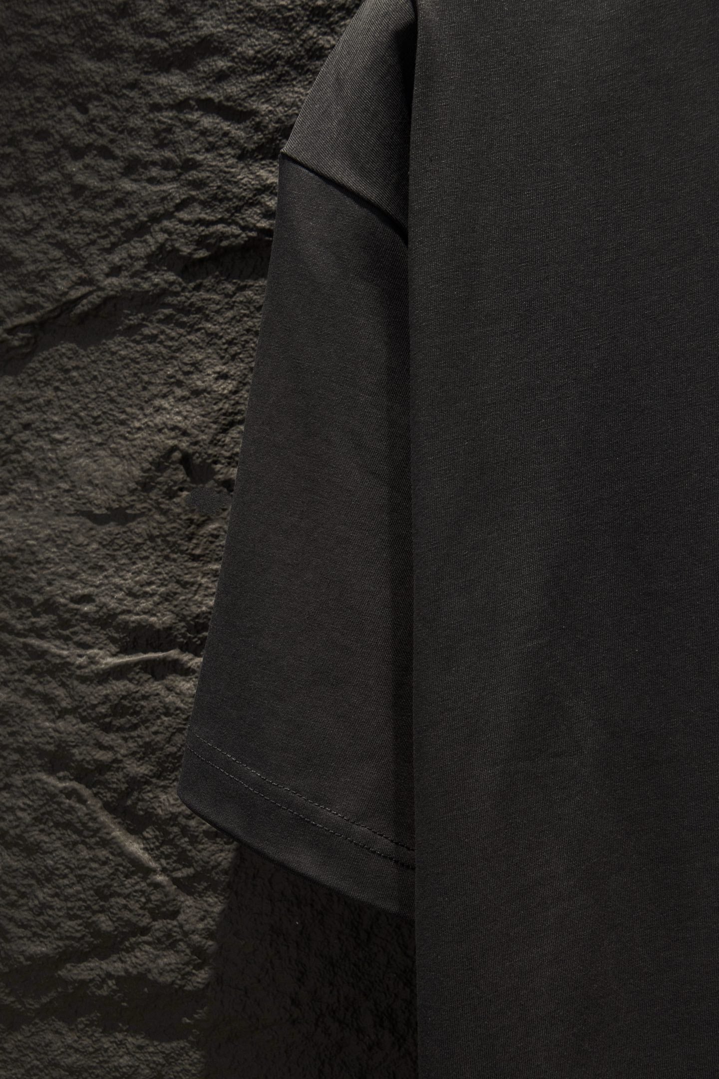 Black short-sleeve T-shirt side view showing drape and hem