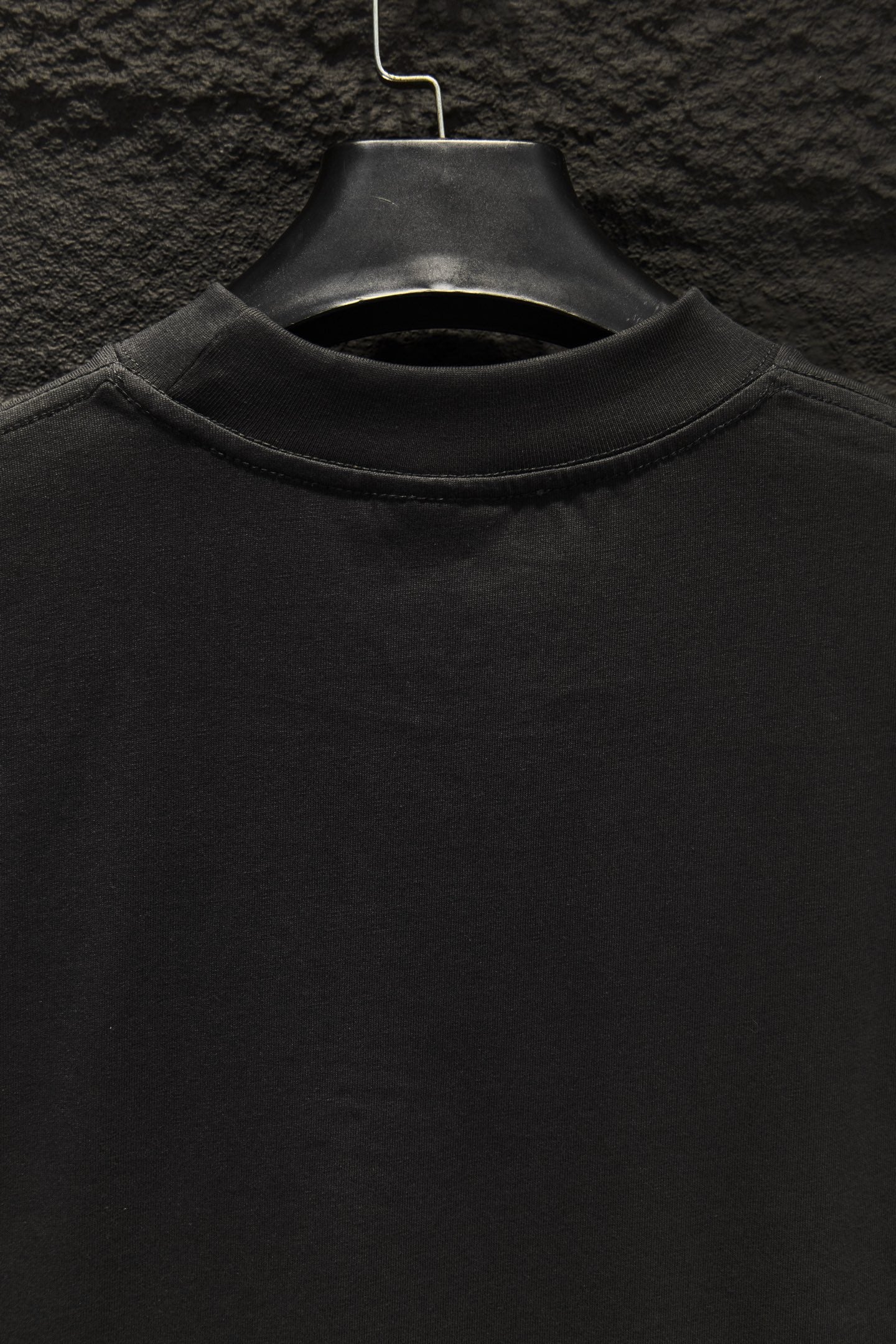 Black crewneck T-shirt collar on a hanger