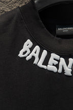 Black T-shirt sleeve with white BALENCIAGA lettering print.
