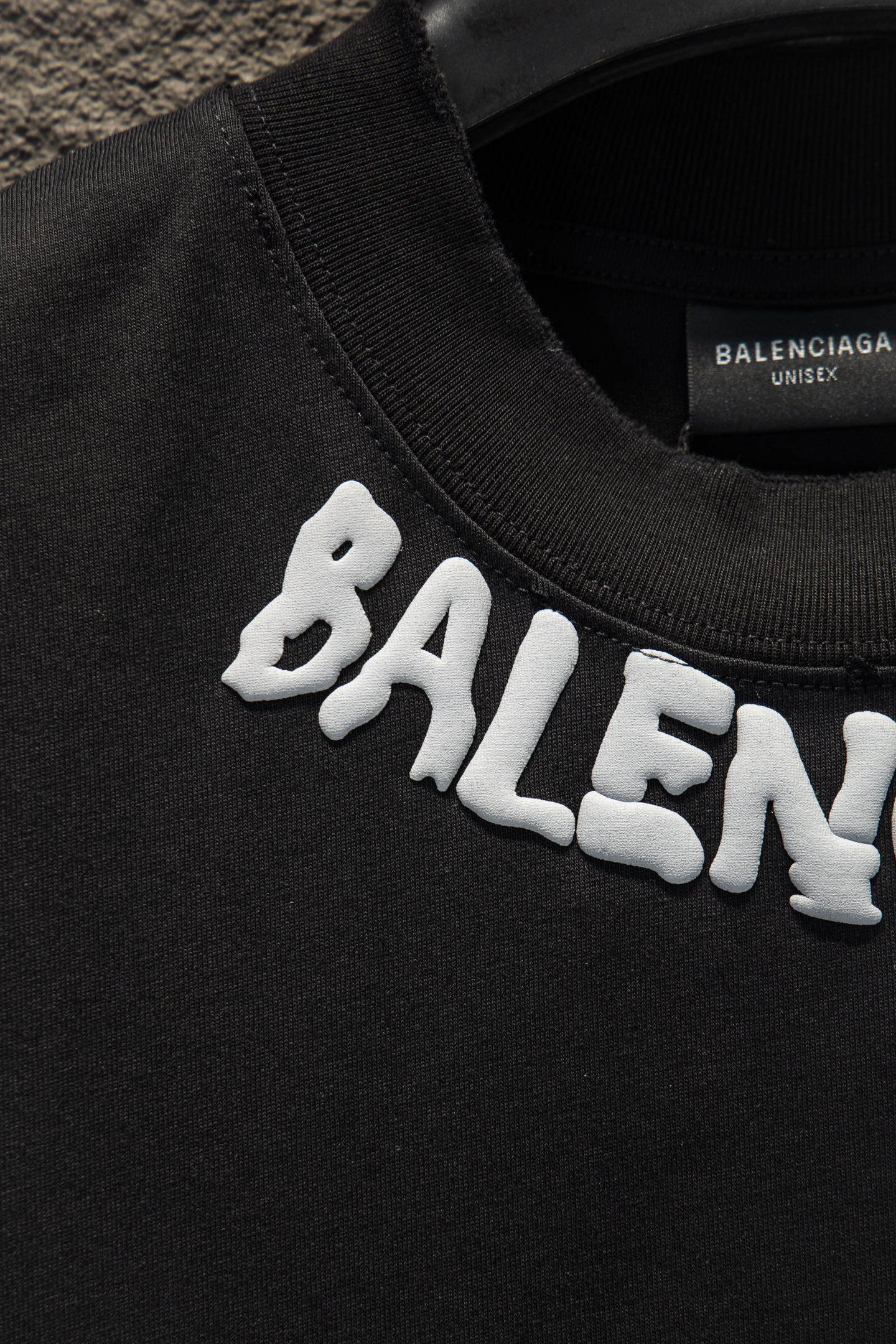 Black T-shirt sleeve with white BALENCIAGA lettering print.
