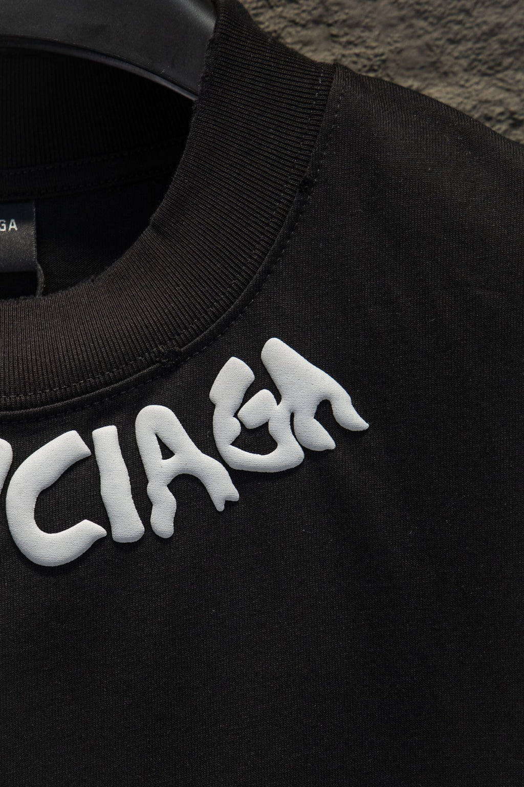 Black T-shirt collar with white BALENCIAGA lettering detail.