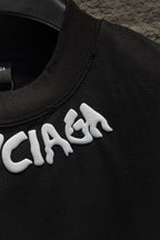Black T-shirt collar with white BALENCIAGA lettering detail.
