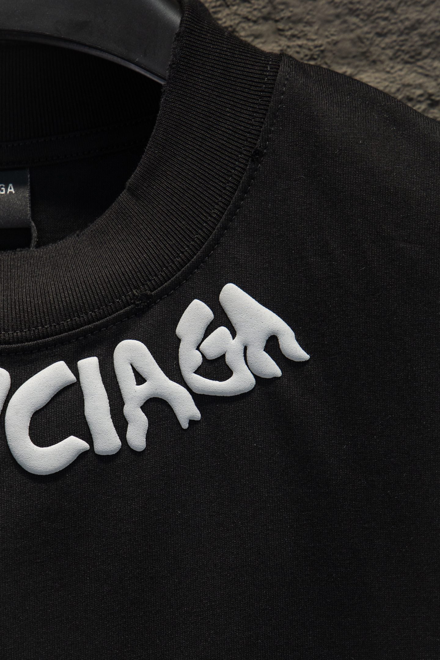 Black T-shirt collar with white BALENCIAGA lettering detail.
