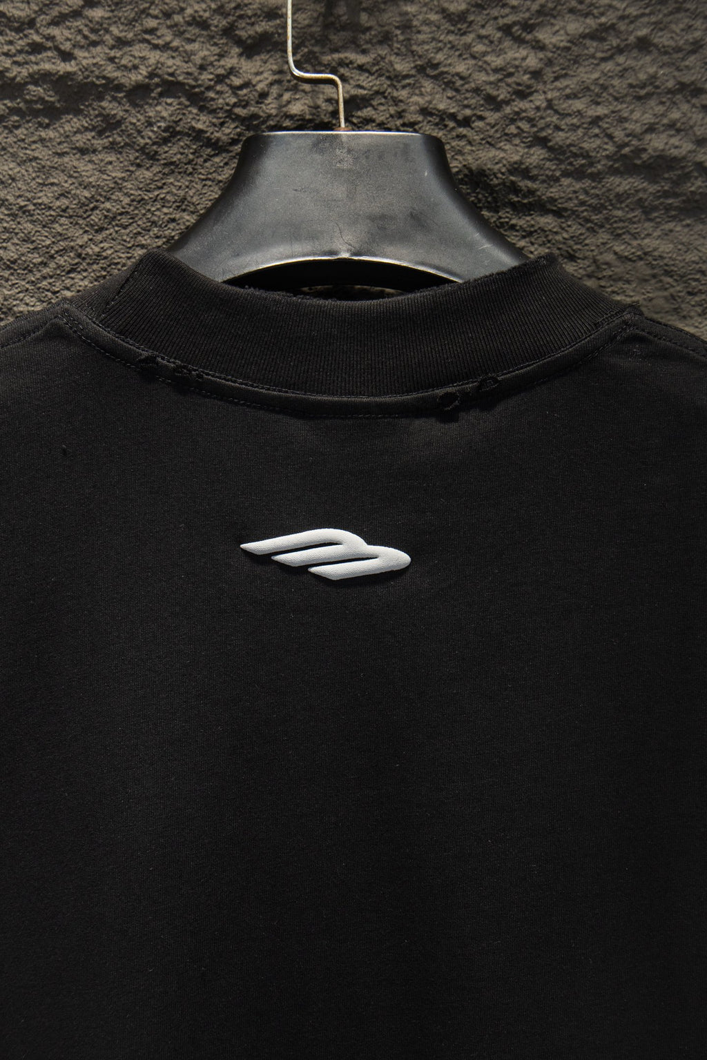 Black short-sleeve T-shirt with small white logo emblem on chest.