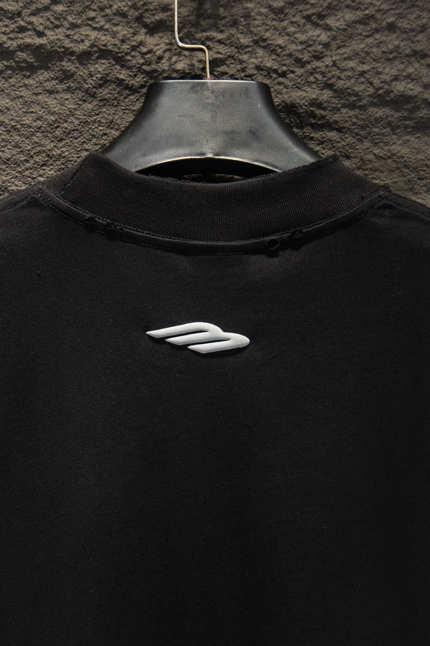 Black short-sleeve T-shirt with small white logo emblem on chest.