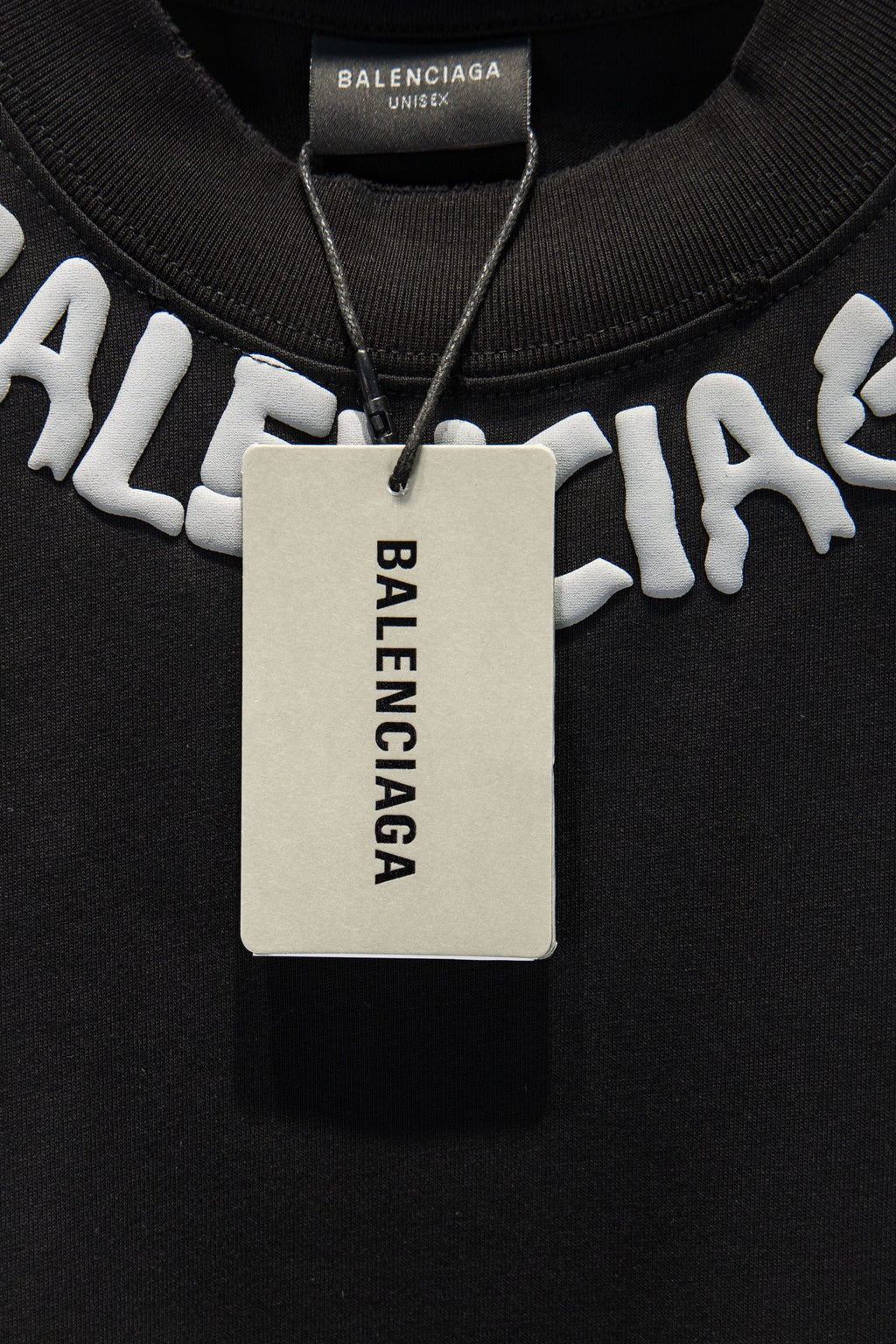 Black T-shirt with hanging tag and large white BALENCIAGA logo.