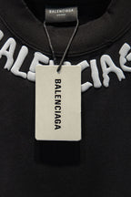 Black T-shirt with hanging tag and large white BALENCIAGA logo.