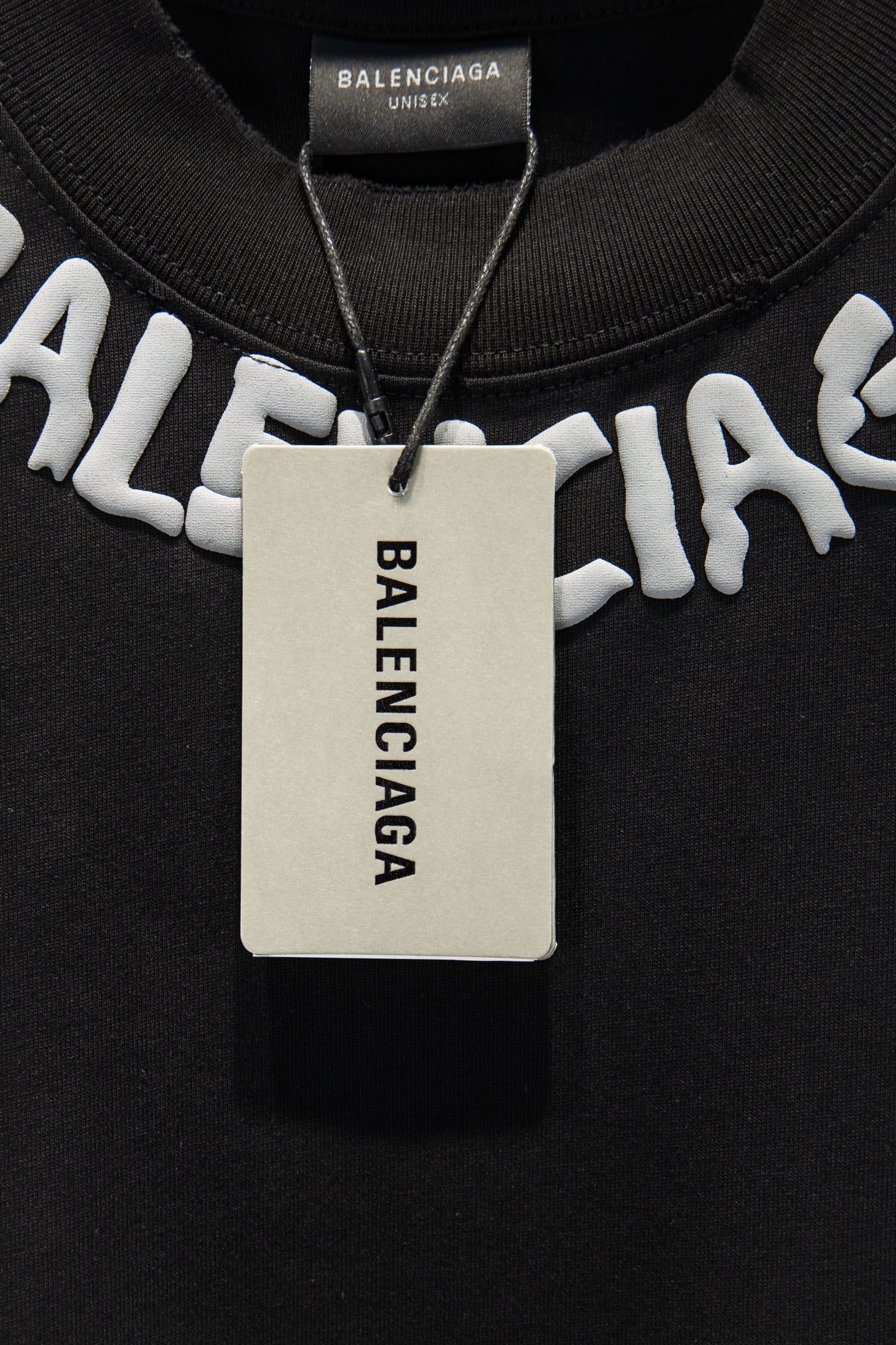 Black T-shirt with hanging tag and large white BALENCIAGA logo.