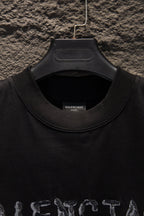 Black short-sleeve T-shirt with ribbed crew neck and top of graphic.
