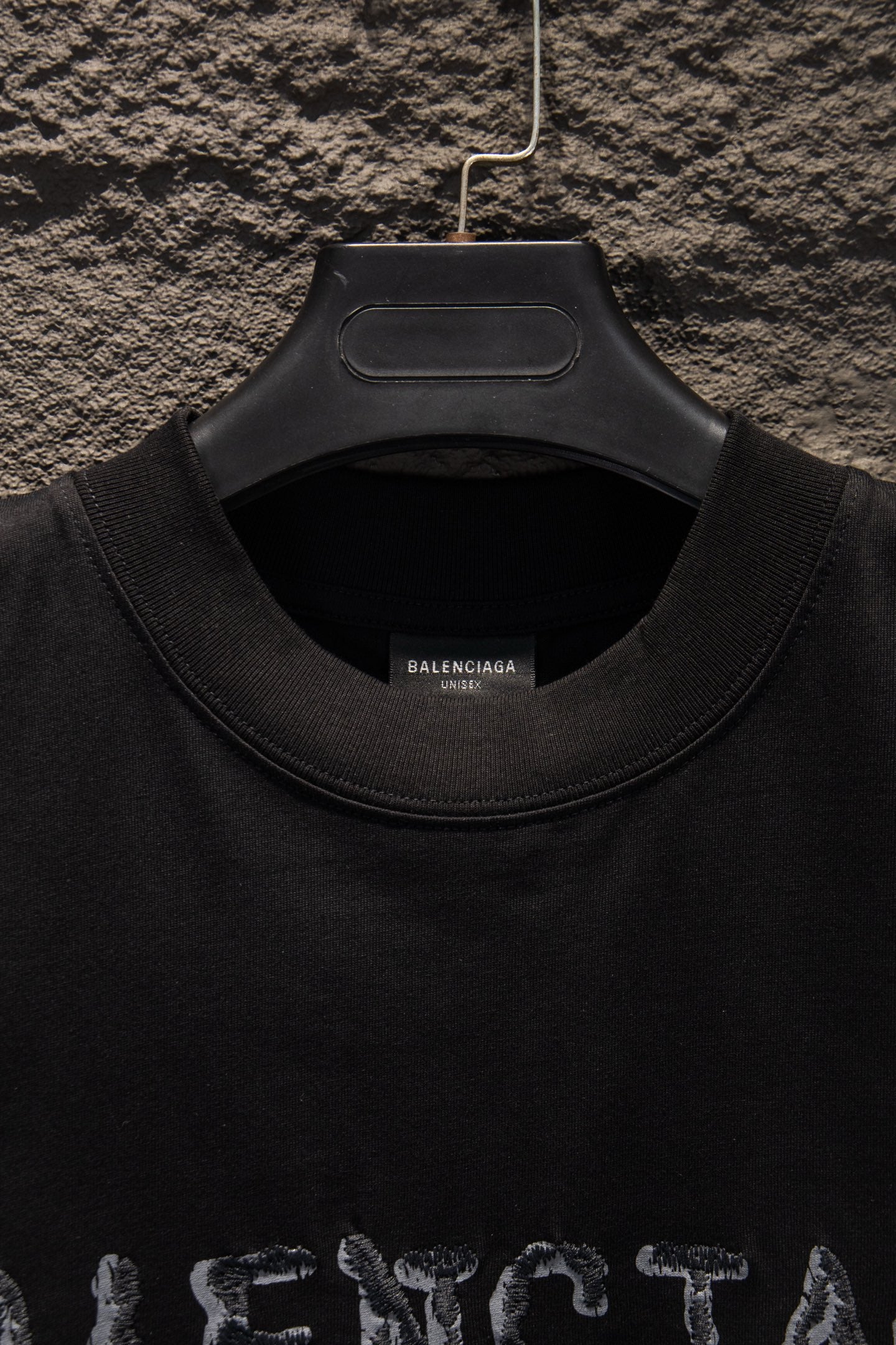 Black short-sleeve T-shirt with ribbed crew neck and top of graphic.
