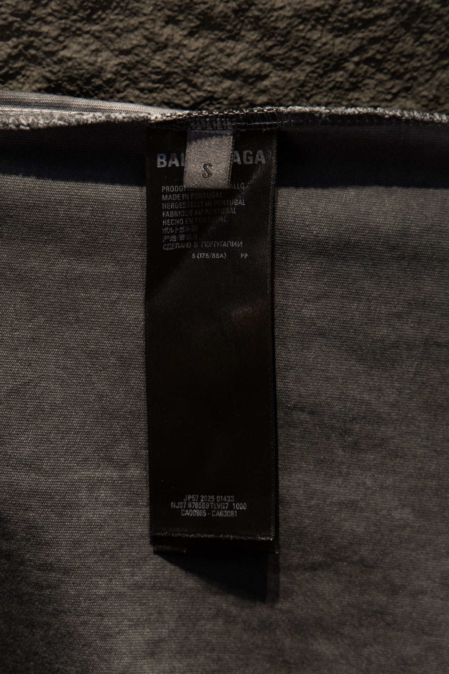 Black care label inside light gray T-shirt near neckline