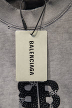 Light gray T-shirt neckline with hanging Balenciaga tag and studded logo