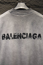 Light gray T-shirt with black BALENCIAGA rhinestone logo across upper back