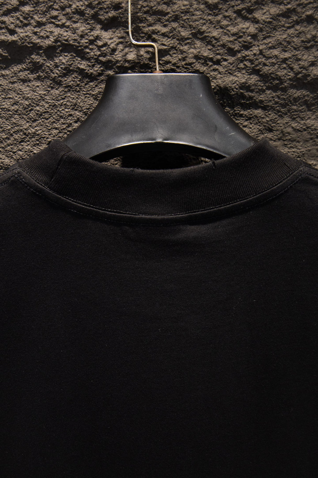 Black T-shirt collar close-up with ribbed crew neck and hanger