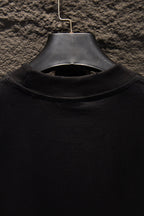 Black T-shirt collar close-up with ribbed crew neck and hanger