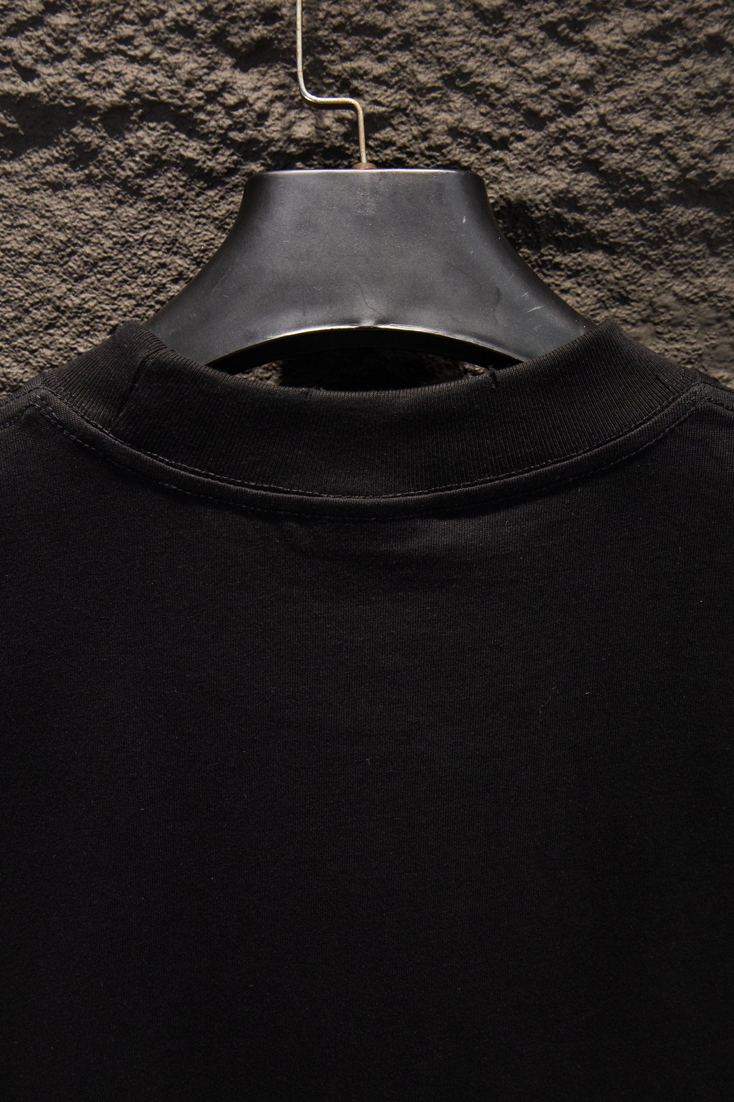 Black T-shirt collar close-up with ribbed crew neck and hanger