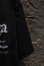 Black T-shirt close-up of sleeve and lower side with partial distressed print