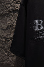Black T-shirt side view with partial distressed logo print near the sleeve