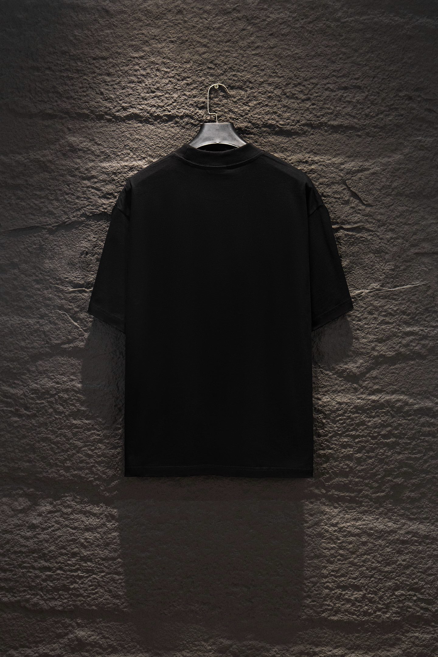 Black crewneck T-shirt with short sleeves, plain back view on a hanger