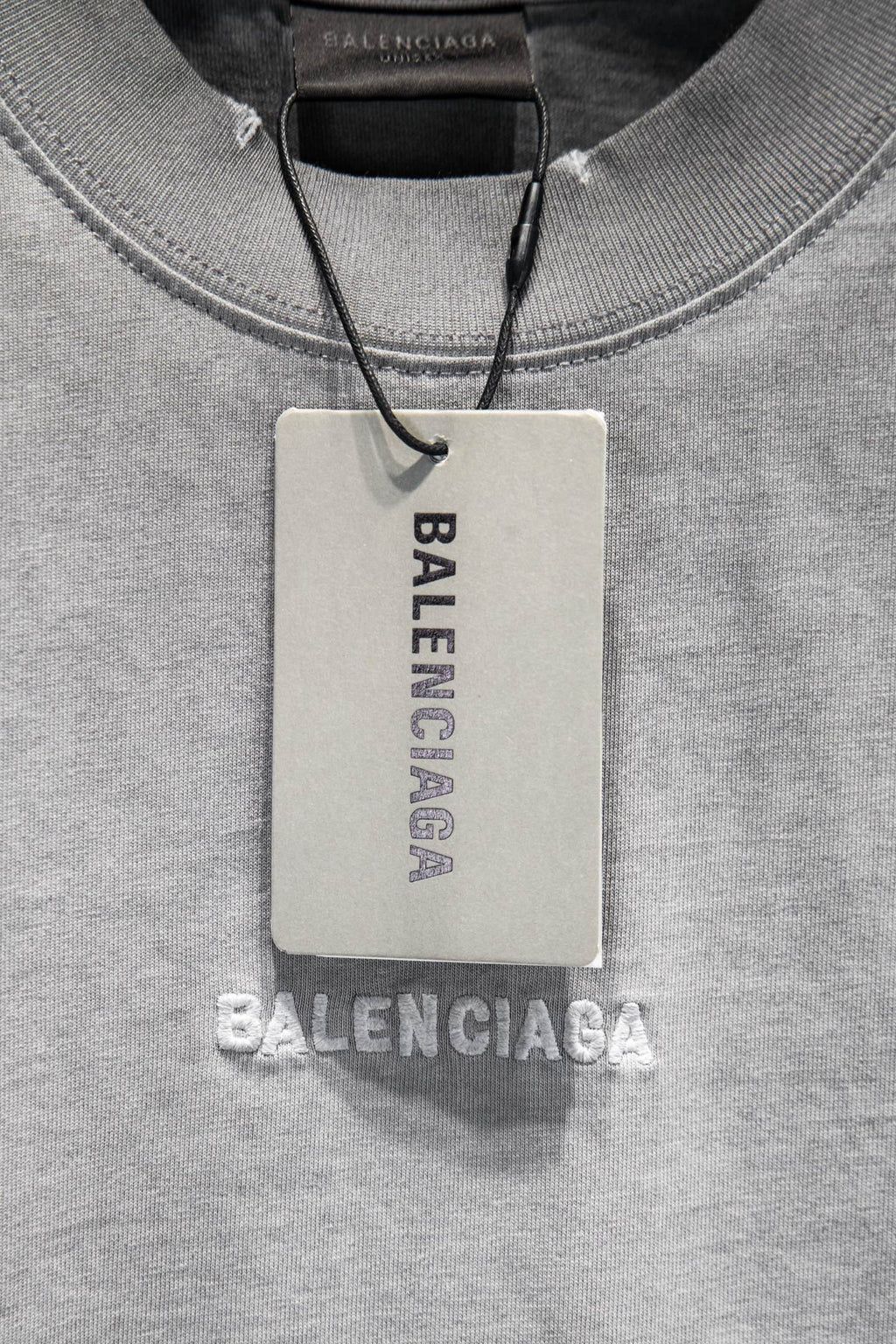 Balenciaga T-shirt with hanging tag at crew neckline and 'BALENCIAGA' branding.