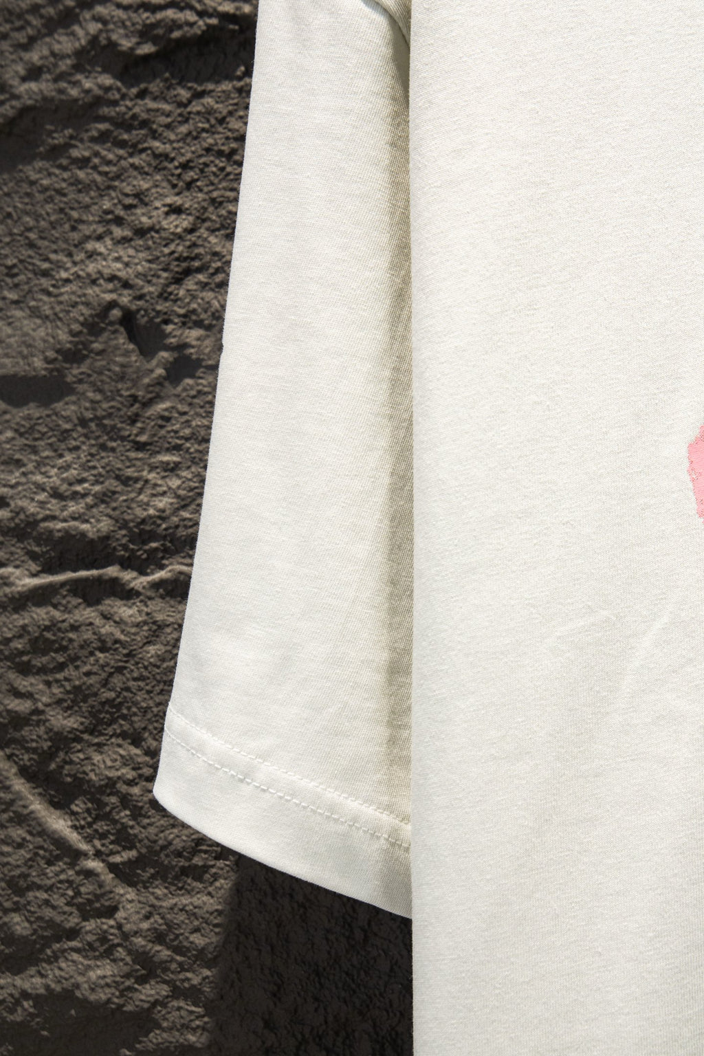 White T-shirt sleeve and side panel detail with visible hem stitching