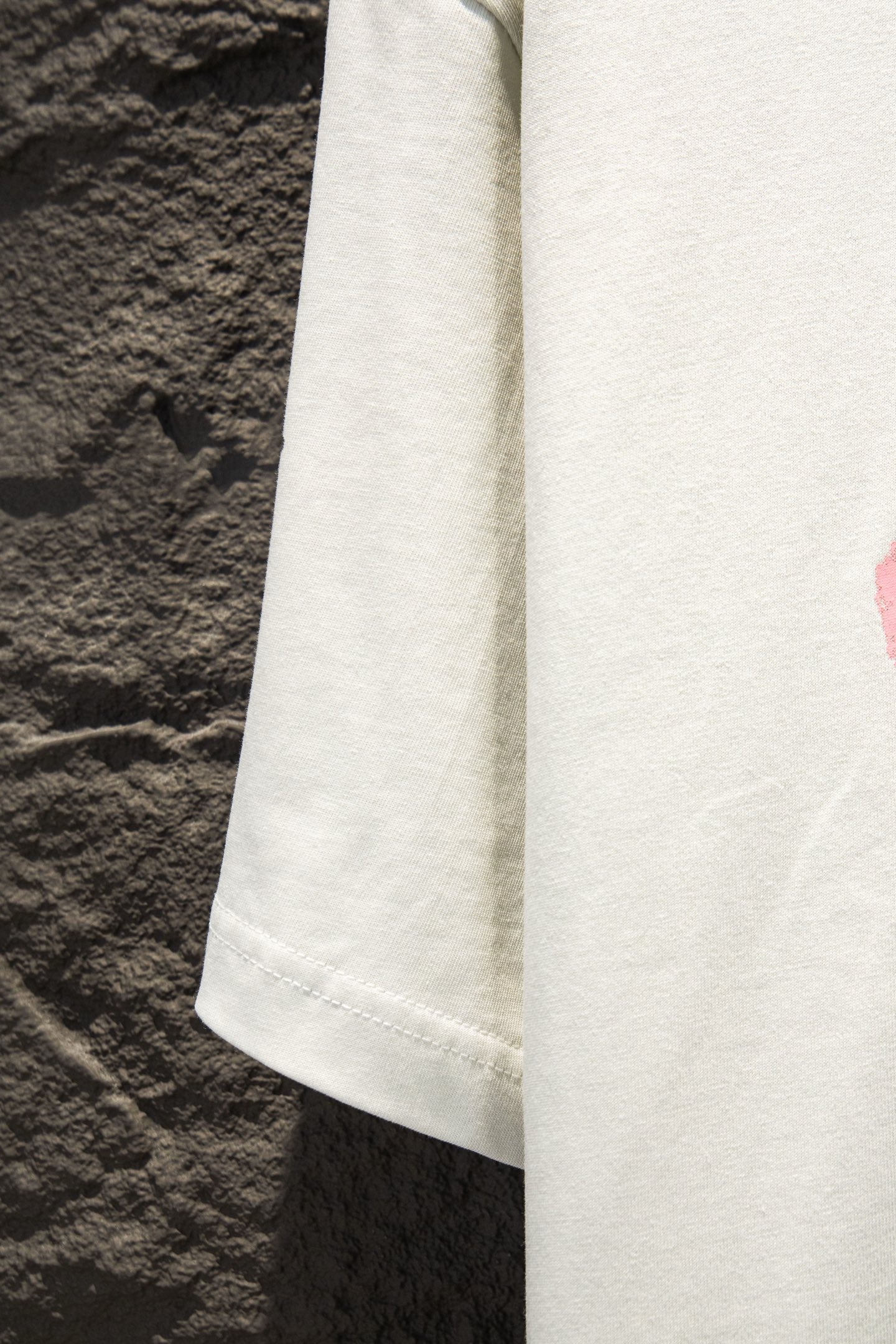 White T-shirt sleeve and side panel detail with visible hem stitching