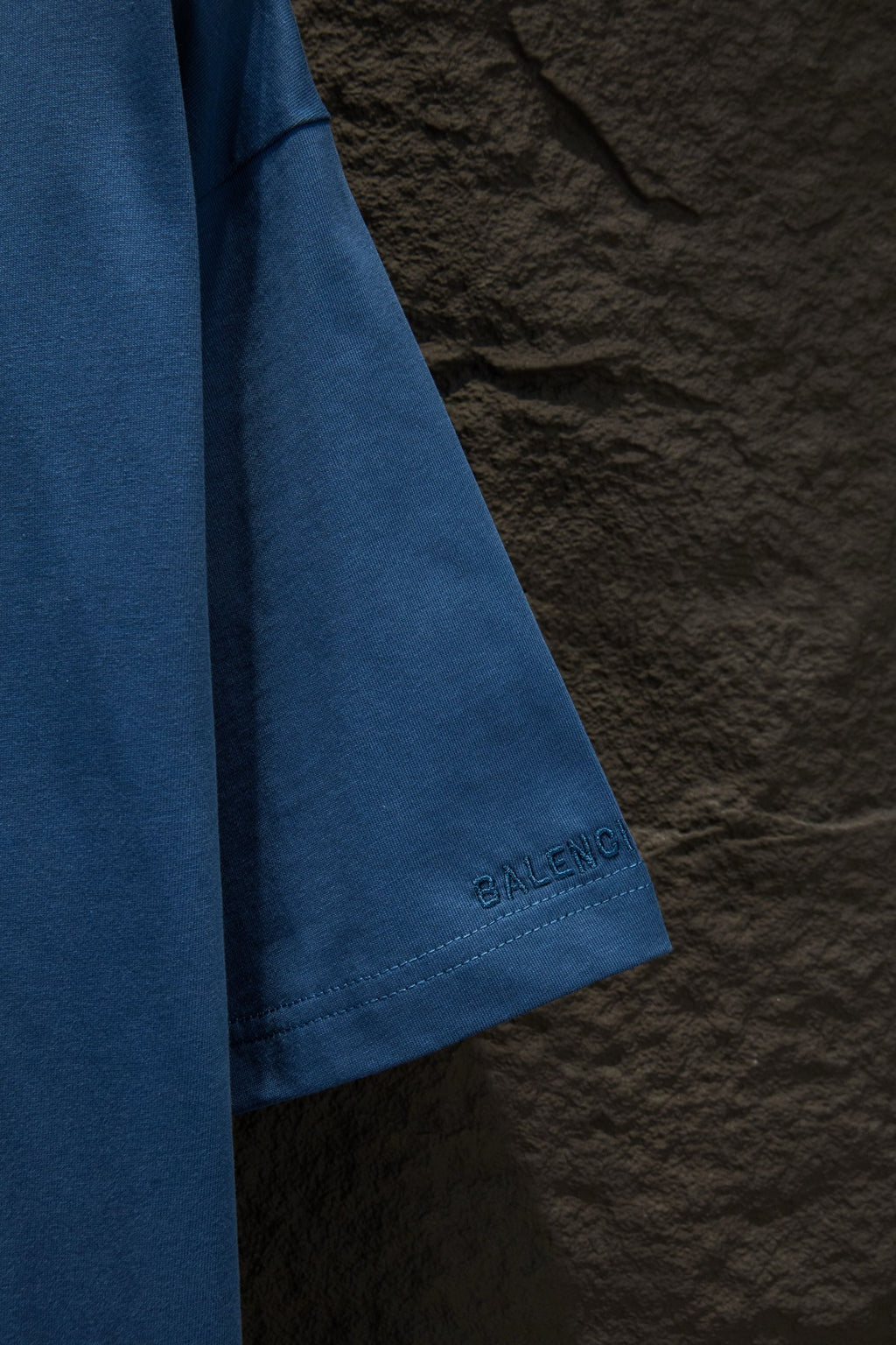 Blue T-shirt sleeve with small Balenciaga logo stamp near the hem