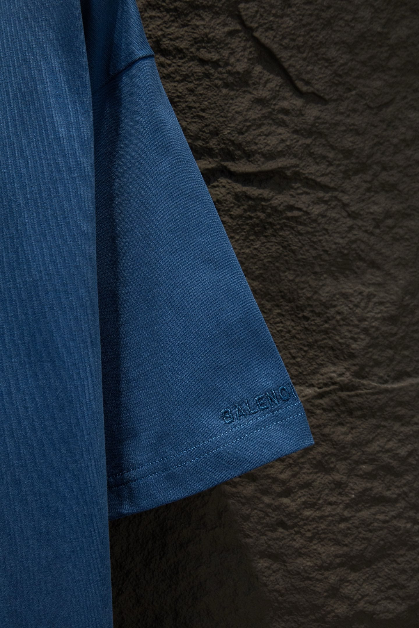 Blue T-shirt sleeve with small Balenciaga logo stamp near the hem