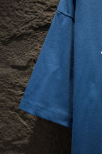 Blue T-shirt side view with curved hem and stitched sleeve cuff
