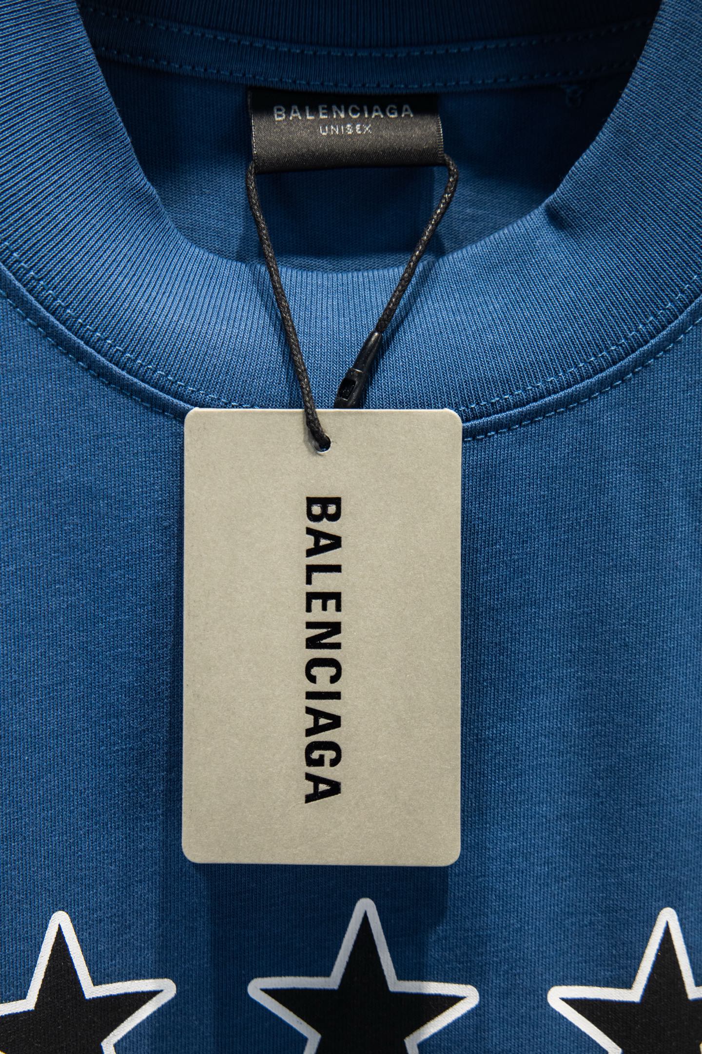 Blue T-shirt neck close-up with hanging Balenciaga tag and star graphics