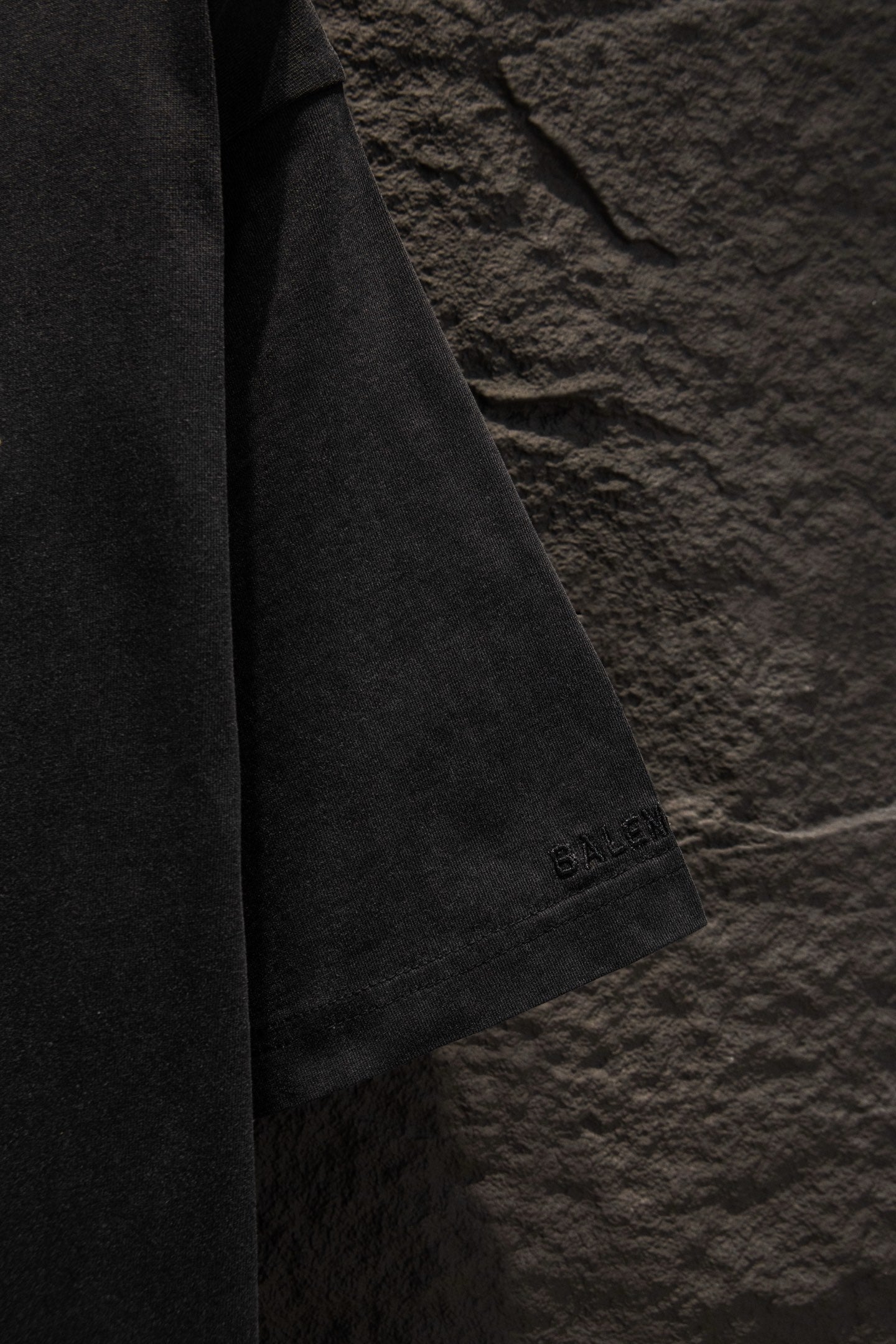 Black T-shirt sleeve with small “BALENCIAGA” embroidery near the hem