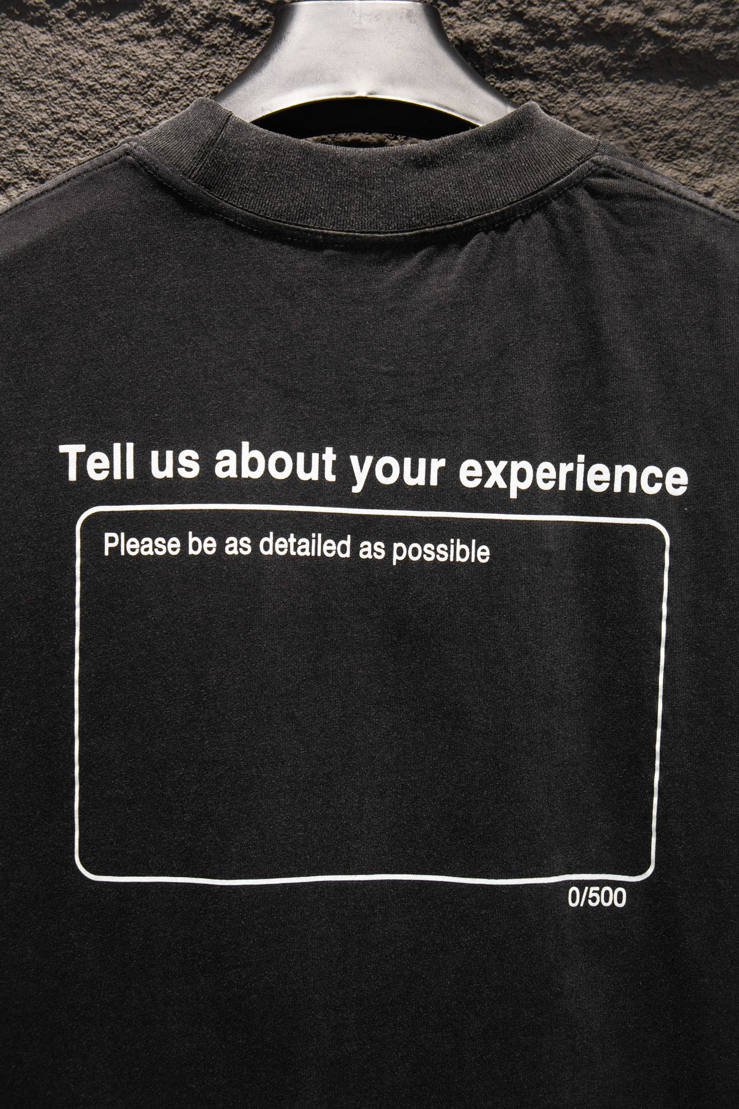 Black crewneck T-shirt with “Tell us about your experience” front graphic