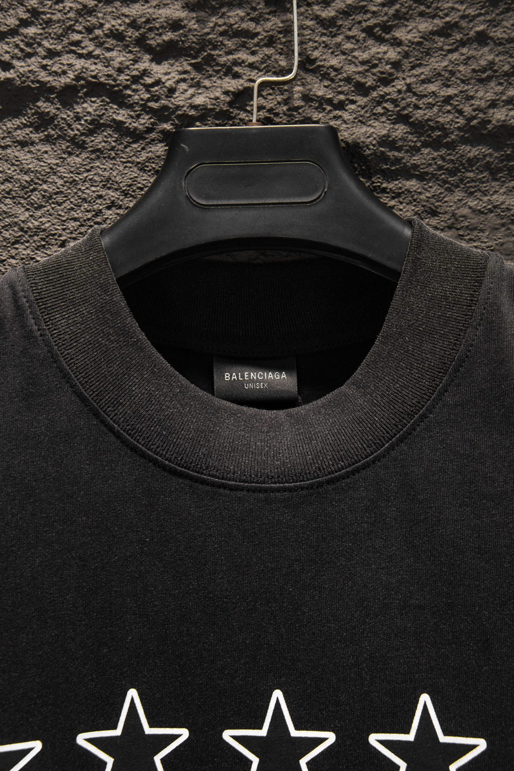 Black crewneck T-shirt neckline with inner label and star print partially visible