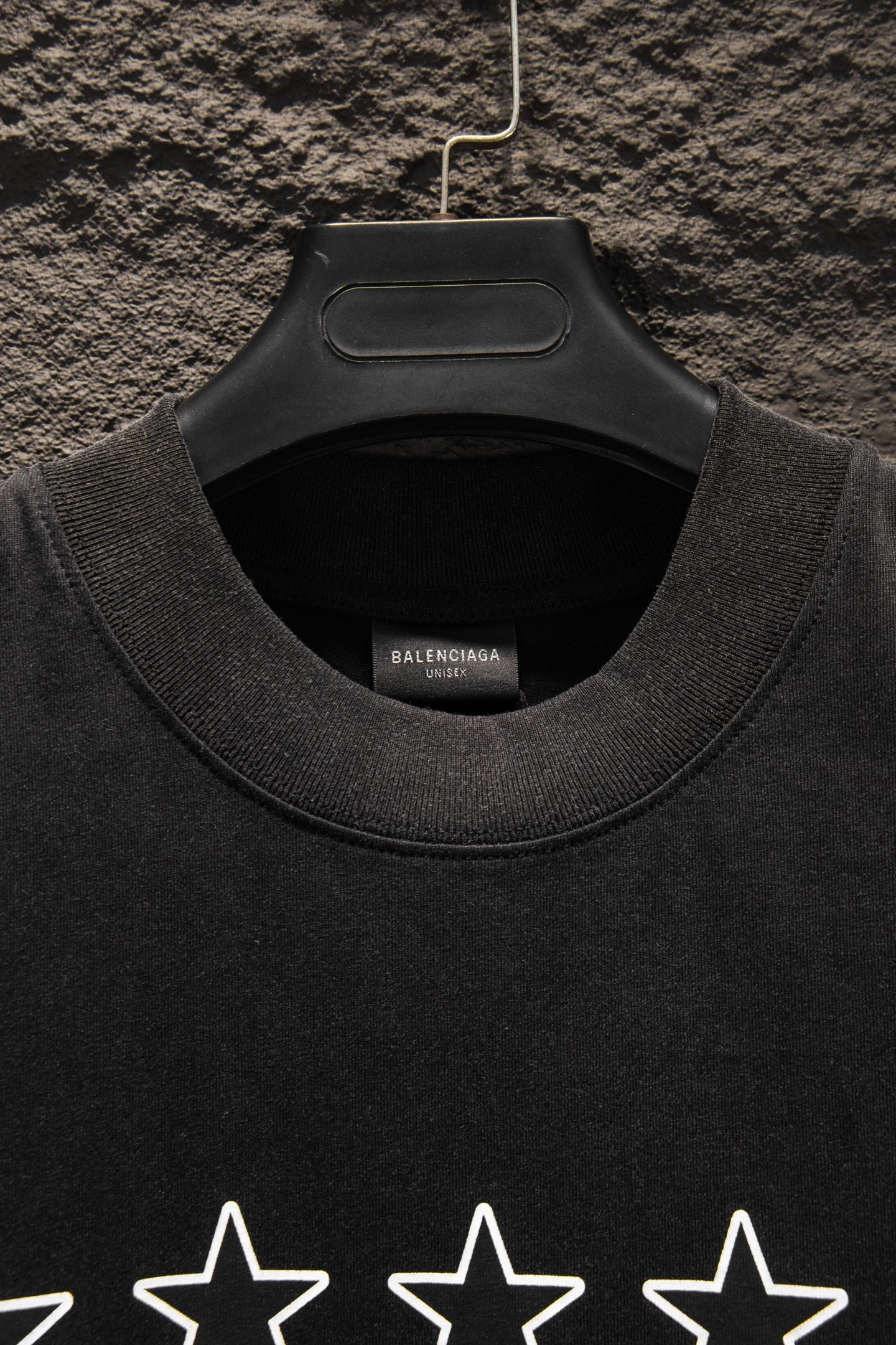 Black crewneck T-shirt neckline with inner label and star print partially visible