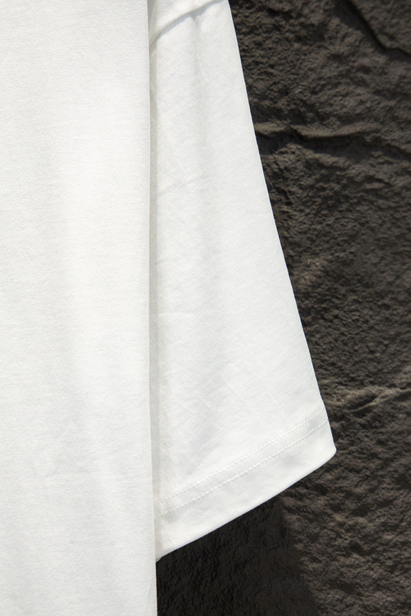 White short-sleeve T-shirt side view with straight hem and visible seam stitching.