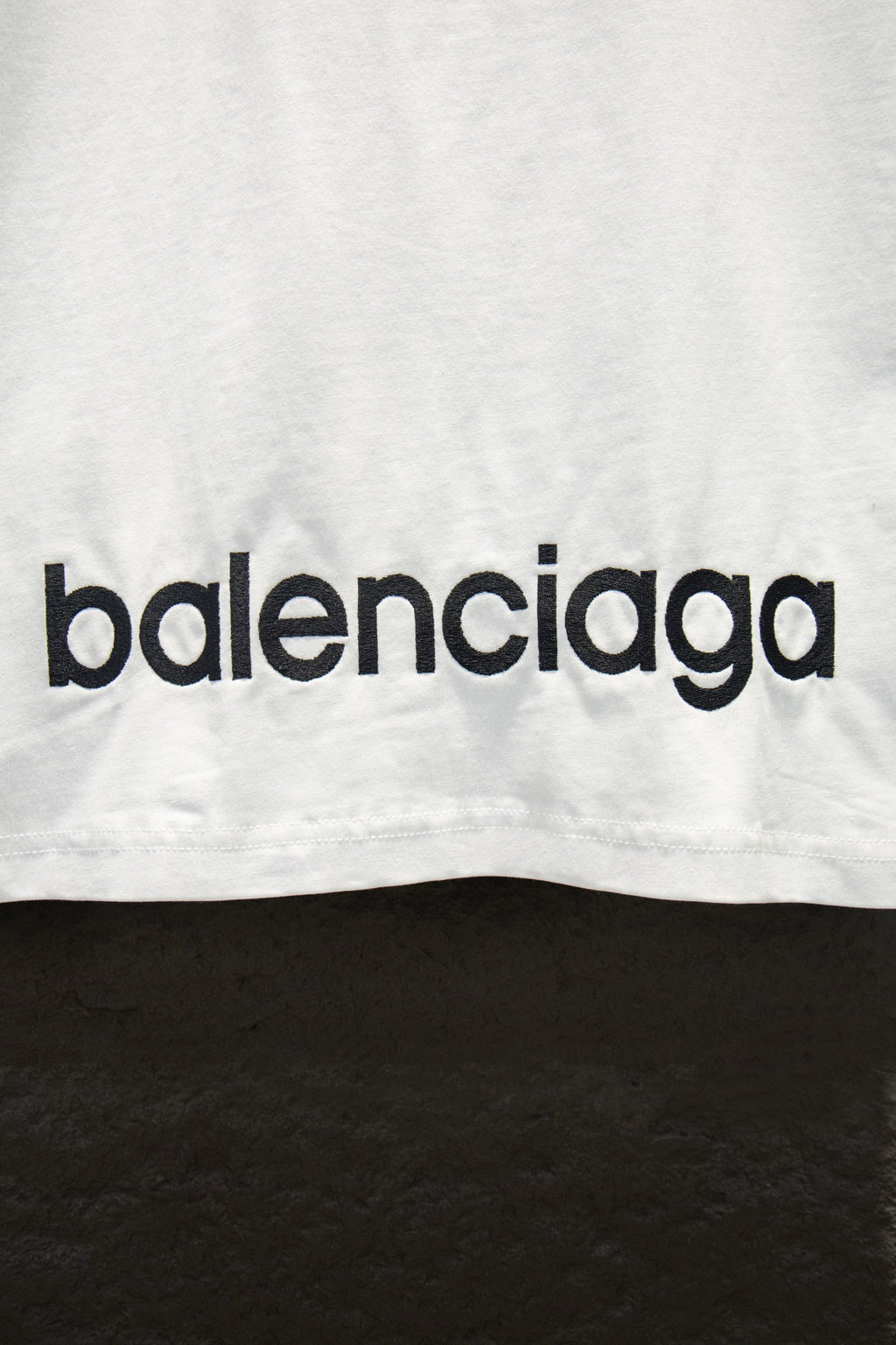 White T-shirt with black balenciaga logo lettering near bottom edge.