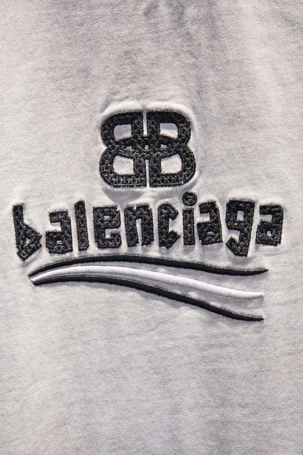 Light gray T-shirt with black Balenciaga logo print and curved stripe detail