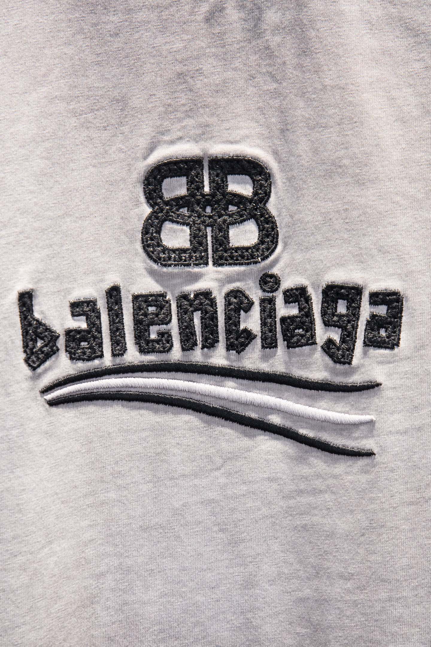 Light gray T-shirt with black Balenciaga logo print and curved stripe detail