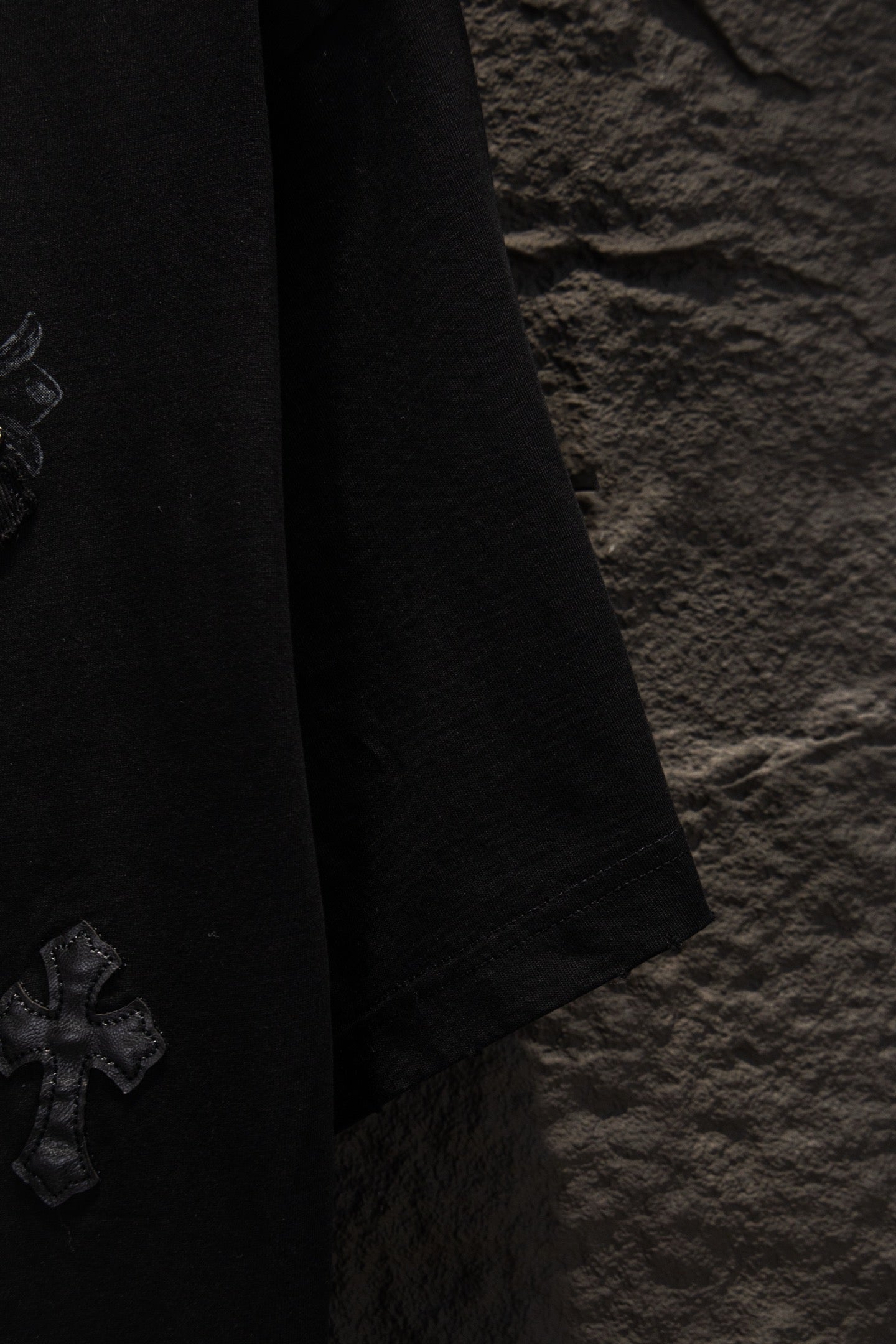 Black T-shirt sleeve with stitched hem and small side logo