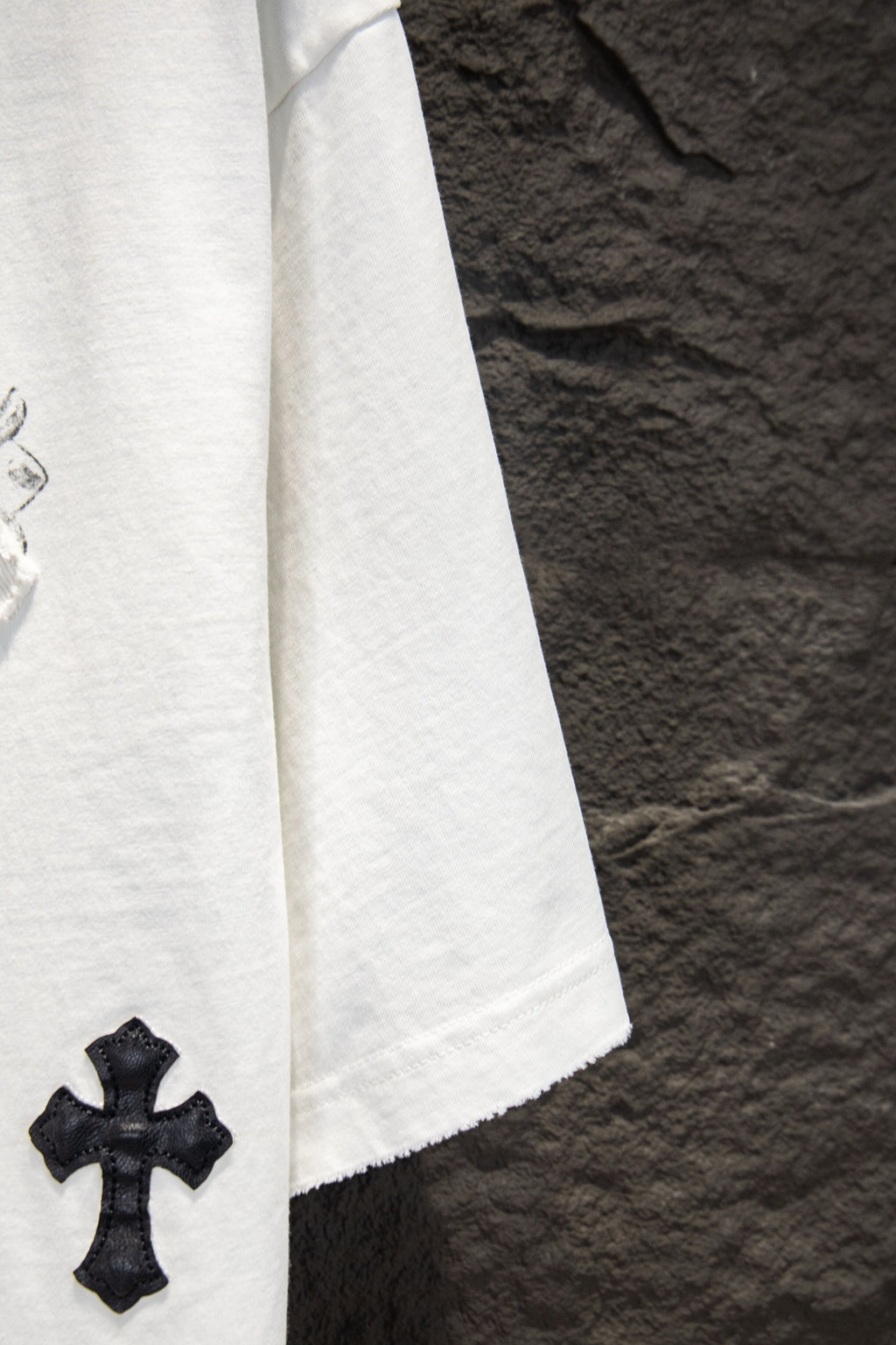 White short-sleeve T-shirt sleeve with small black cross patch