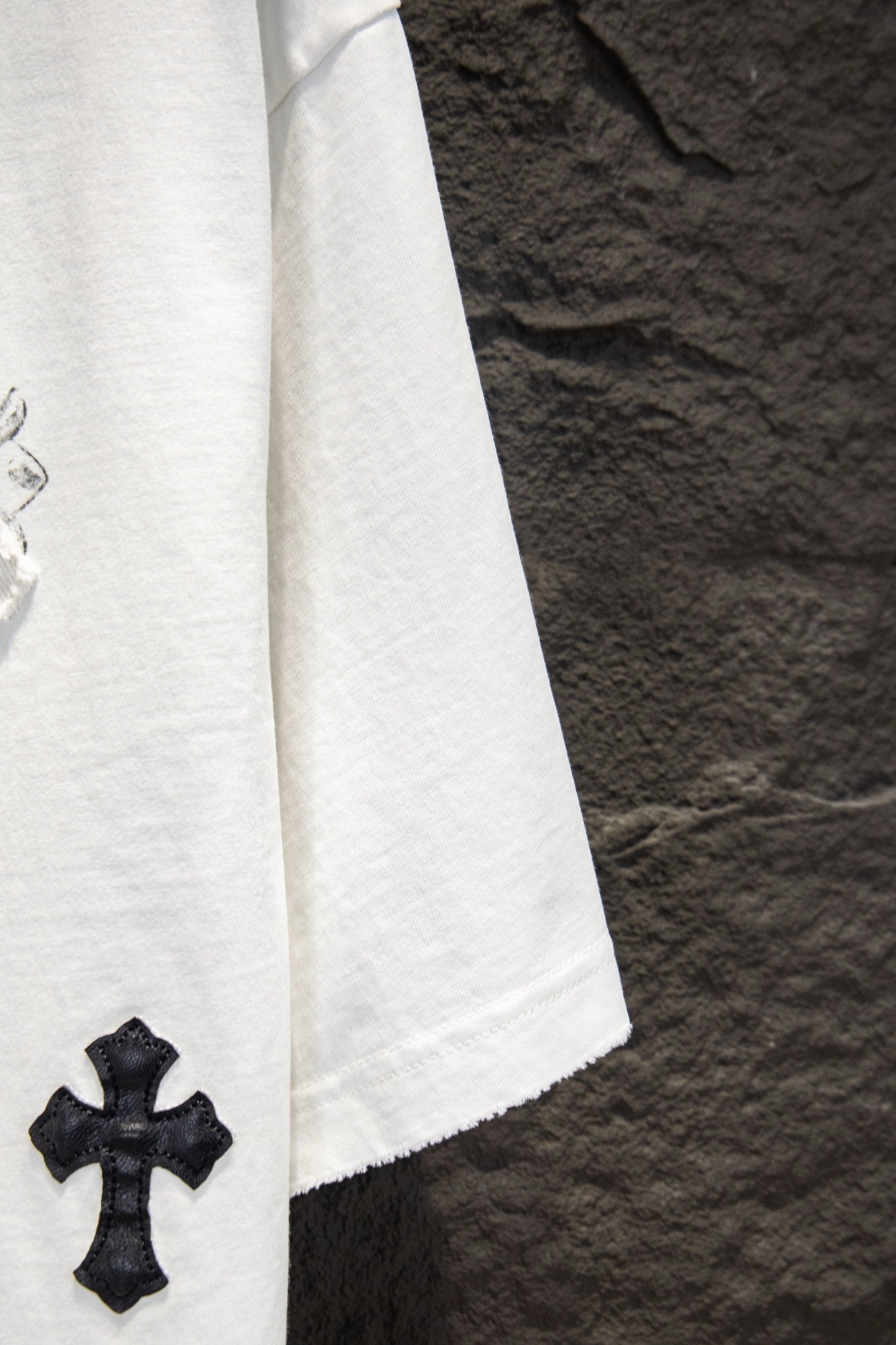 White short-sleeve T-shirt sleeve with small black cross patch
