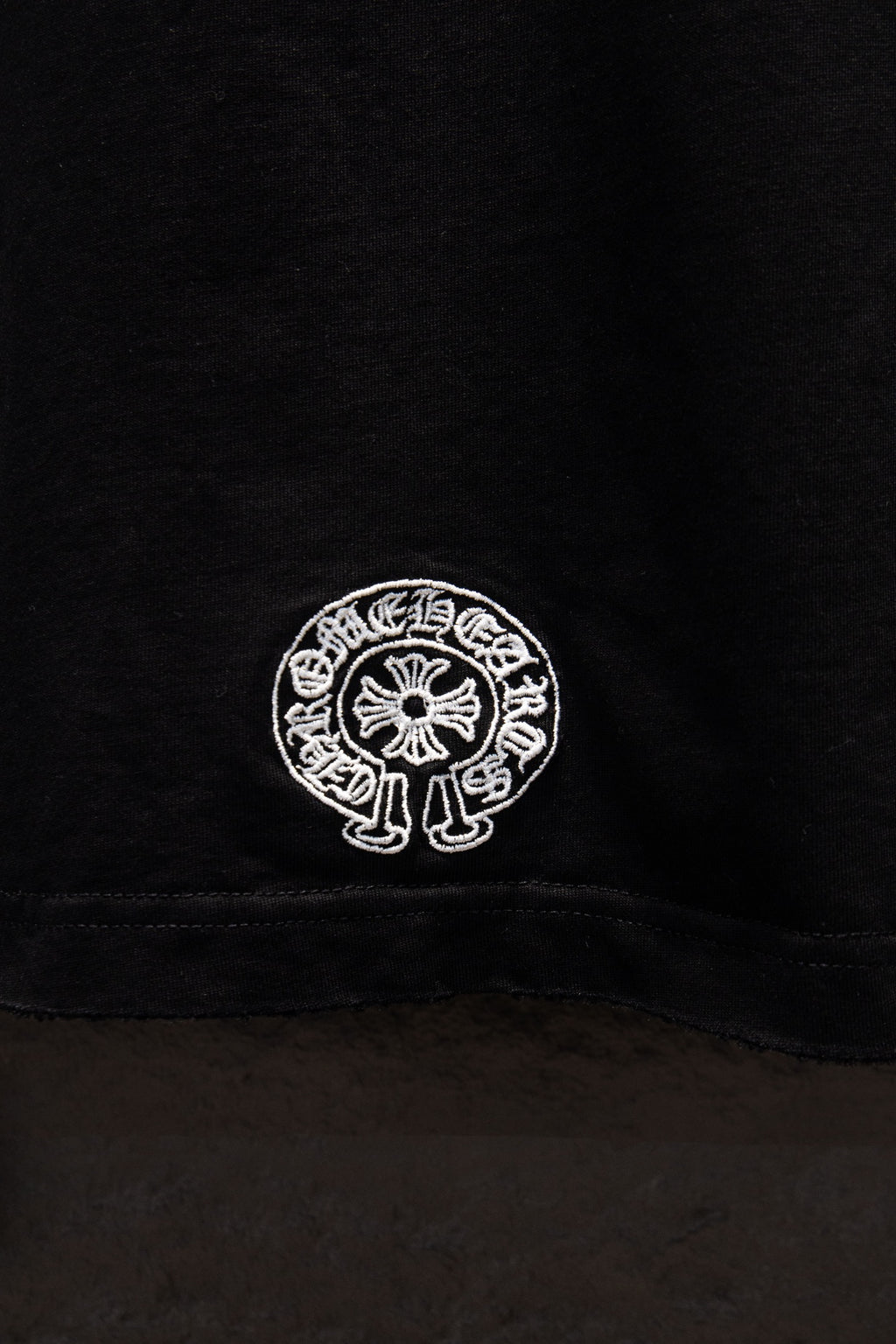 Black short-sleeve T-shirt lower back seam with small white circular logo