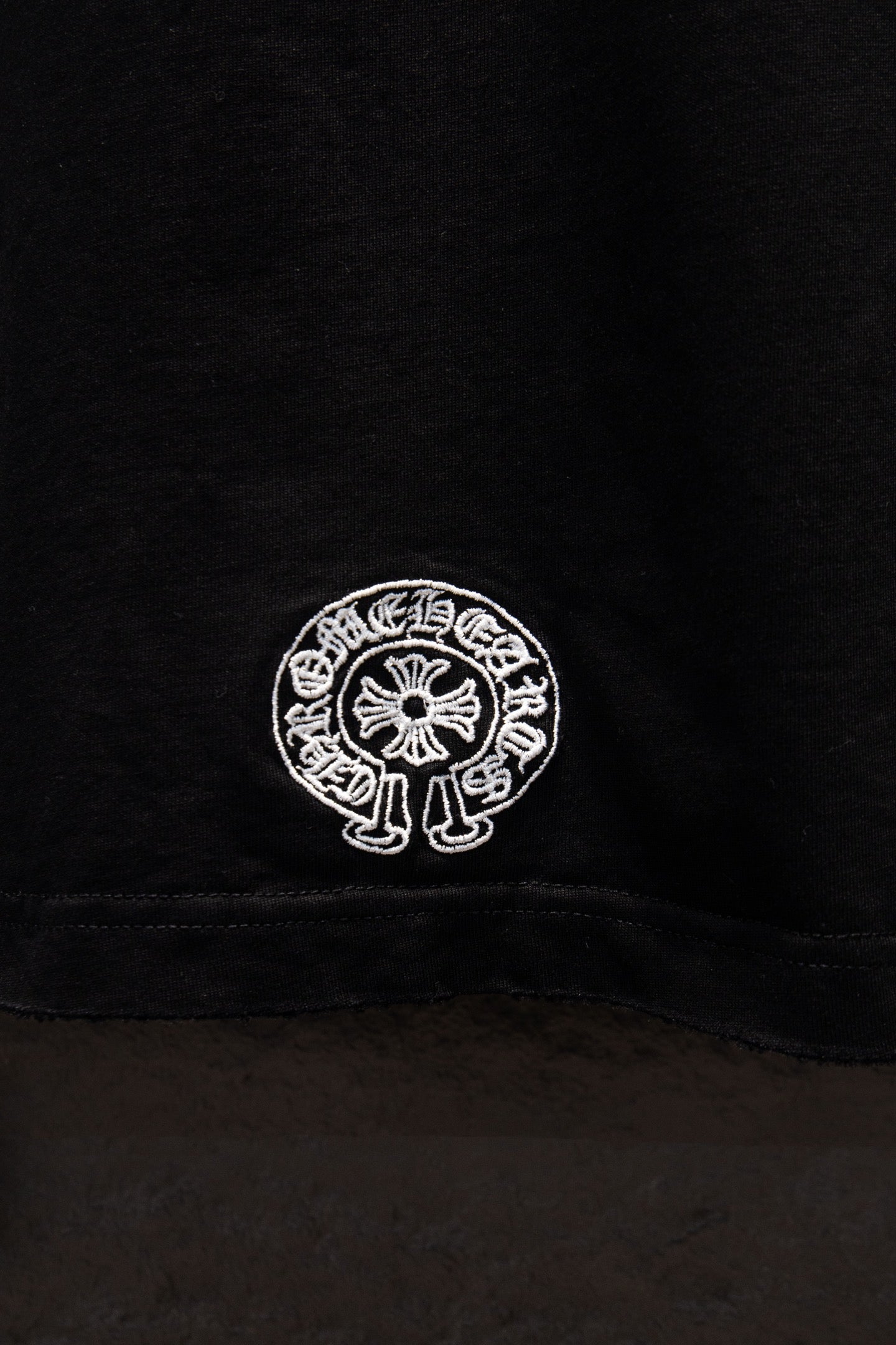 Black short-sleeve T-shirt lower back seam with small white circular logo