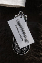 Garment tag reading Chrome Hearts and Combines Operations, hanging from T-shirt.