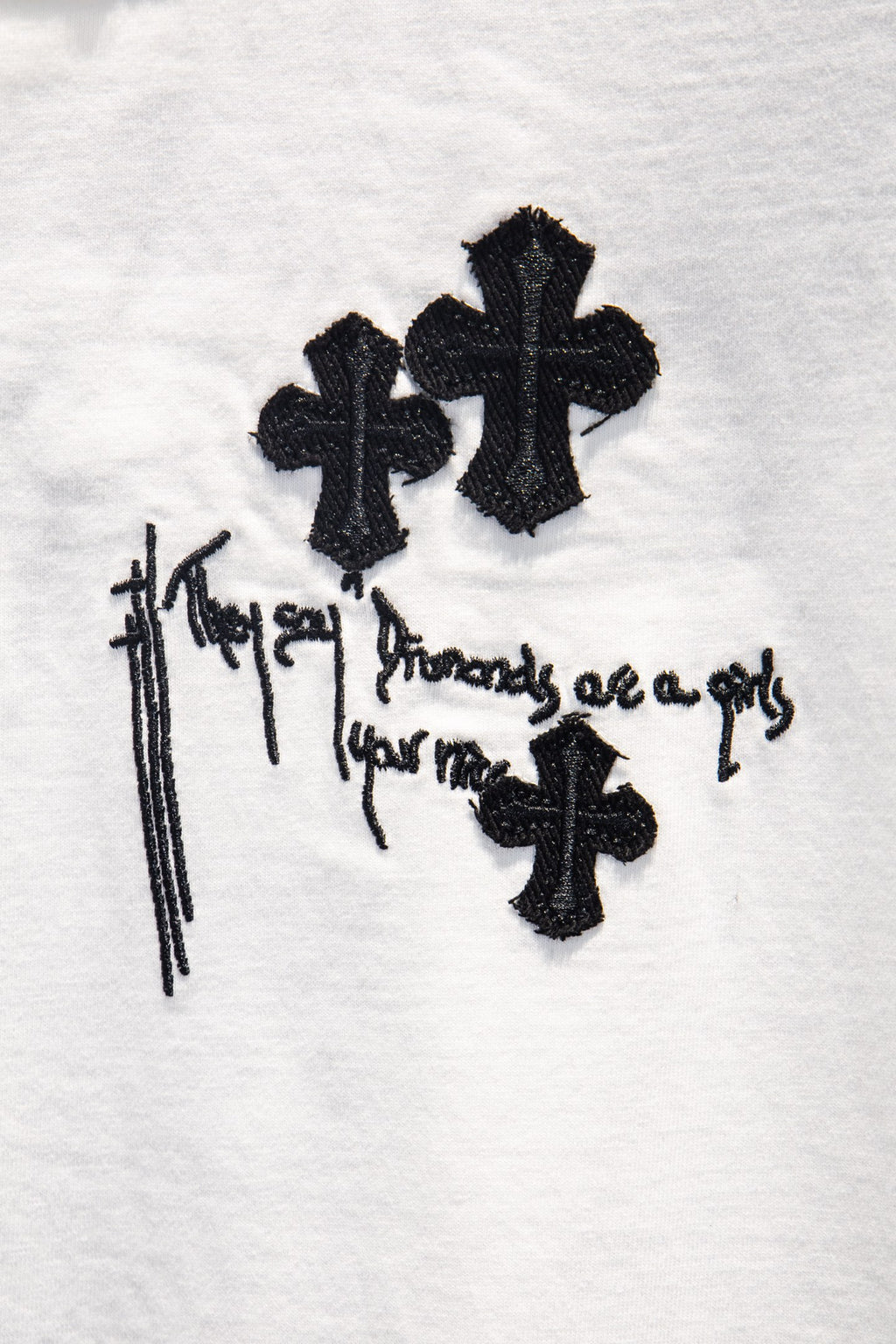 White short-sleeve T-shirt detail: black cross symbols with drips and text graphic.
